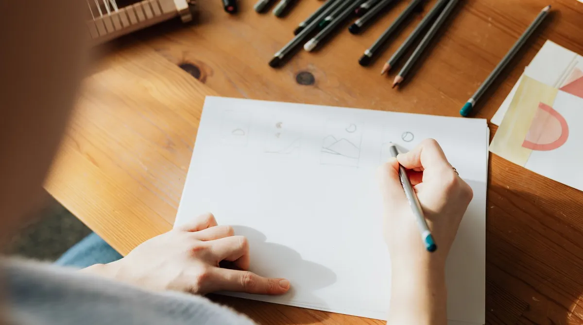 Croquis de plusieurs pistes de logo au crayon sur un bureau en bois, étape de conception d'une identité visuelle